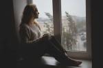 Une fille mélancolique qui regarde par la fenêtre la grisaille de janvier (Crédit : Alex.I)
