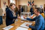 Une électrice remettant sa carte électorale à un assesseur (Crédit : Alex.I)