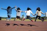 Des jeunes filles qui sautent à l’unisson en se donnant la main (Crédit : Manseok_Kim)