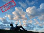 Une personne étendue sur l’herbe regardant les nuages  (Crédit : Alex.I Grok)