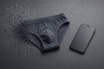 Un slip gris à côté d’un smartphone sur un fond gris (Crédit : Alex.I)