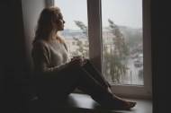Une fille mélancolique qui regarde par la fenêtre la grisaille de janvier (Crédit : Alex.I)