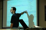 Un enseignant pointant du doigt un tableau avec du code (Crédit : Wonderlane)