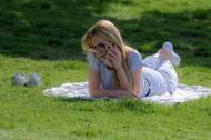 Une femme au téléphone dans un parc en été (Crédit : Surprising_Media)